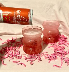 A can of Good Dogg being poured into a glass with the Dragon's Kiss cocktail.
